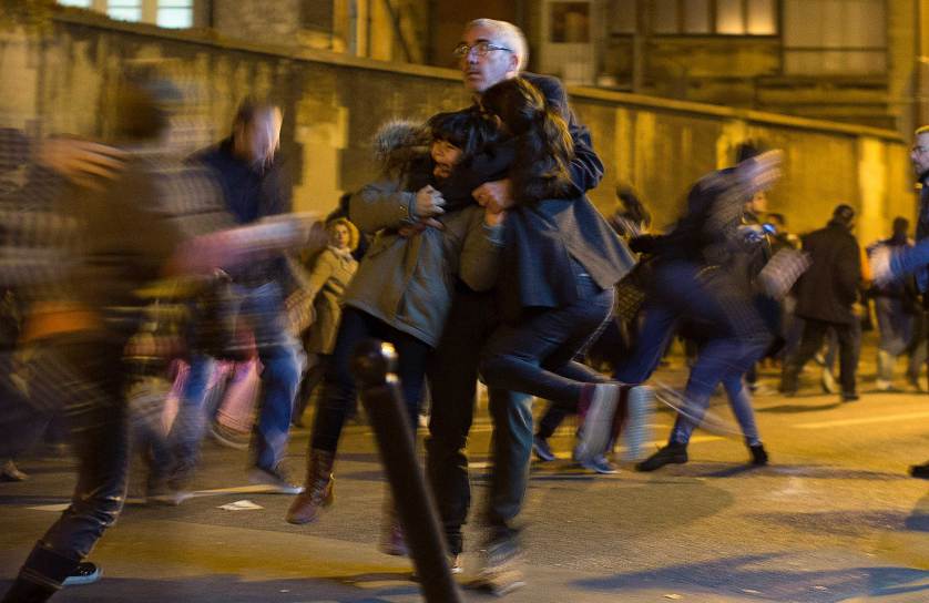 15/11/15: Ένας άντρας κρατά στην αγκαλιά του δυο παιδιά ενώ γύρω όλοι τρέχουν ανεξέλεγκτα, κατά τη διάρκεια ξαφνικού πανικού που ενέσκηψε ενώ γινόταν ολονυκτία για τα θύματα των επιθέσεων στο Παρίσι, κοντά στο ξενοδοχείο Carillon. - AP Photo/Peter Dejong